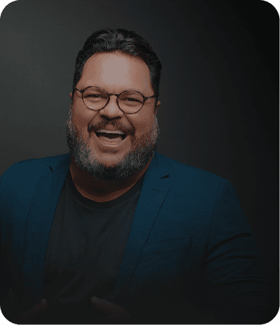 Evento Super Megavendas para concessionárias Um painel digital em cinza e preto com um homem sorridente de óculos, barbudo e camisa social azul. Ele aponta para o centro do painel, onde há vários cartões com textos como 'Equipe engajada', 'Clientes agendados' e 'Meta de vendas batida!'. Na parte inferior, há botões com os textos 'Ligar para cliente', 'Chamar no WhatsApp', 'Agendar tarefa', 'Registrar novo contato' e 'Ver convite'.